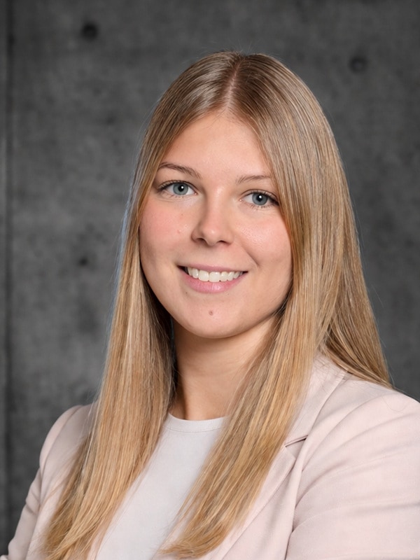 Portrait von Rebecca Moser. Sie hat blonde lange Haare, blaue Augen und trägt ein rosa Jacket.