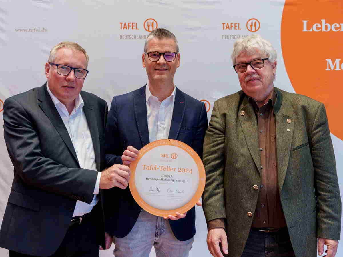 3 Männer stehen nebeneinander, 2 halten eine runde Urkunde mit der Aufschrift Tafel-Teller 2024