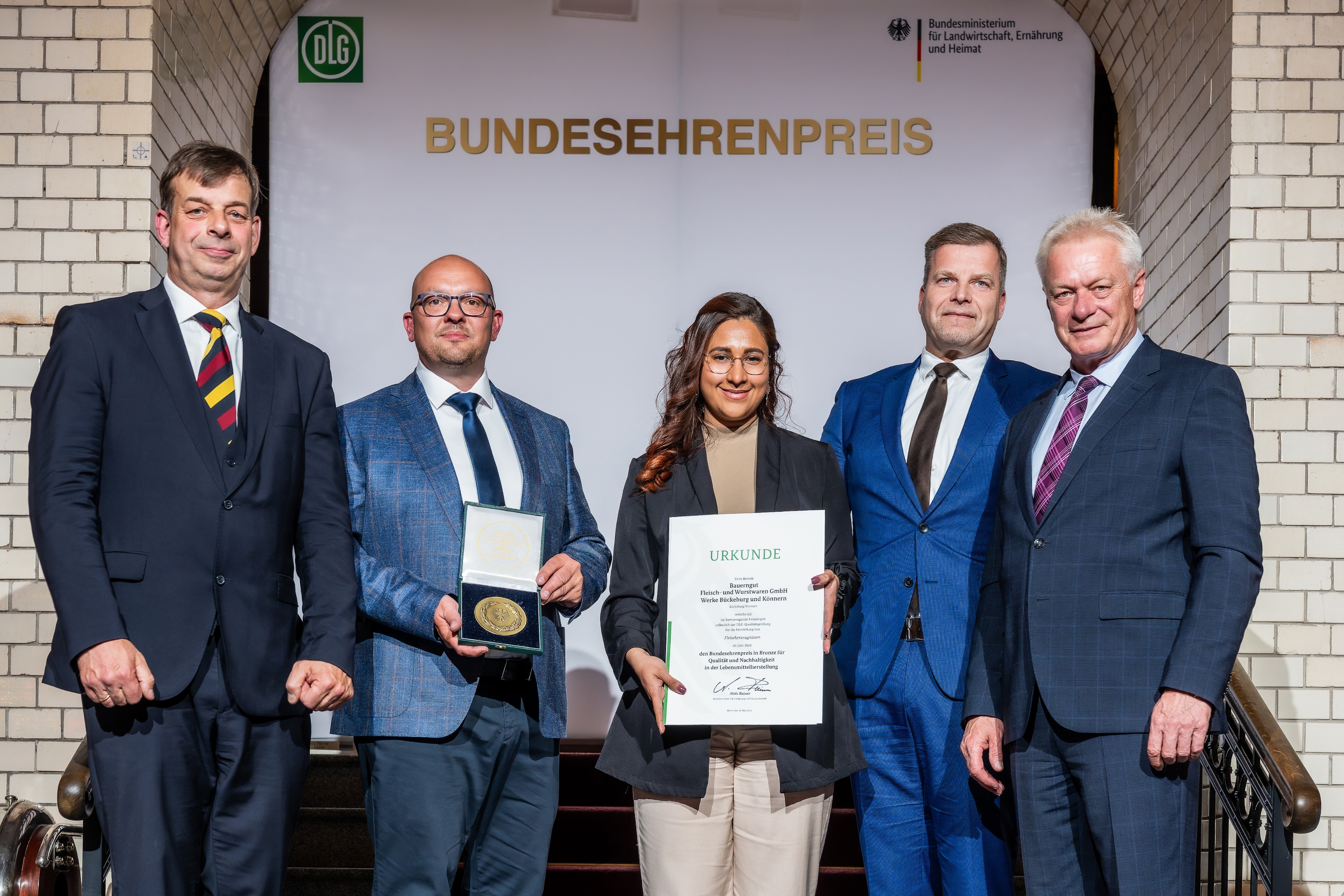 Die drei Bauerngut-Vertreter mit der Urkunde und dem Preis, neben ihnen Bundesminister Alois Reiner und der DLG-Präsident.