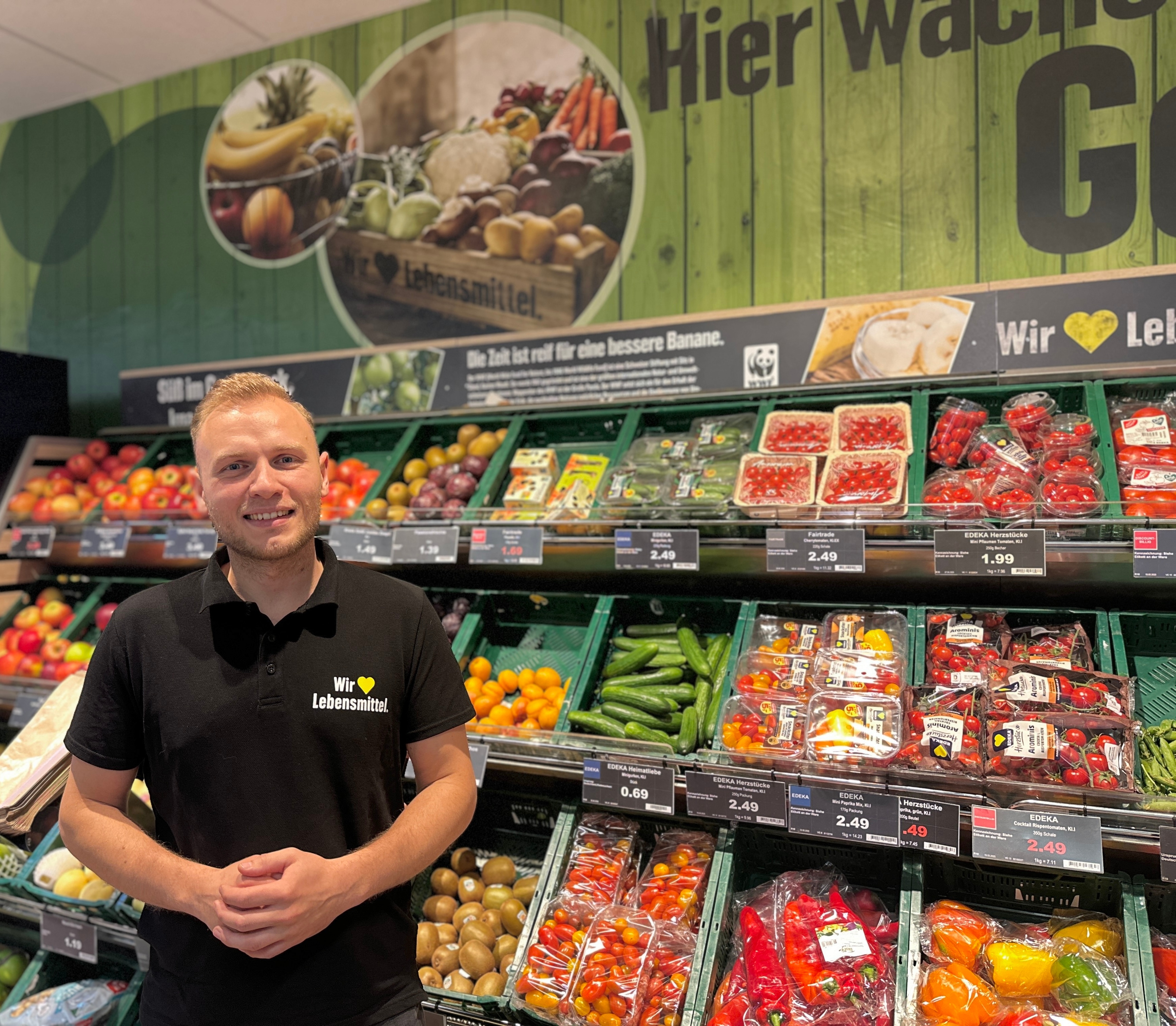 EDEKA-Kaufmann Wilhelm Rauch steht vor dem Obst- und Gemüseregal in seinem Markt.