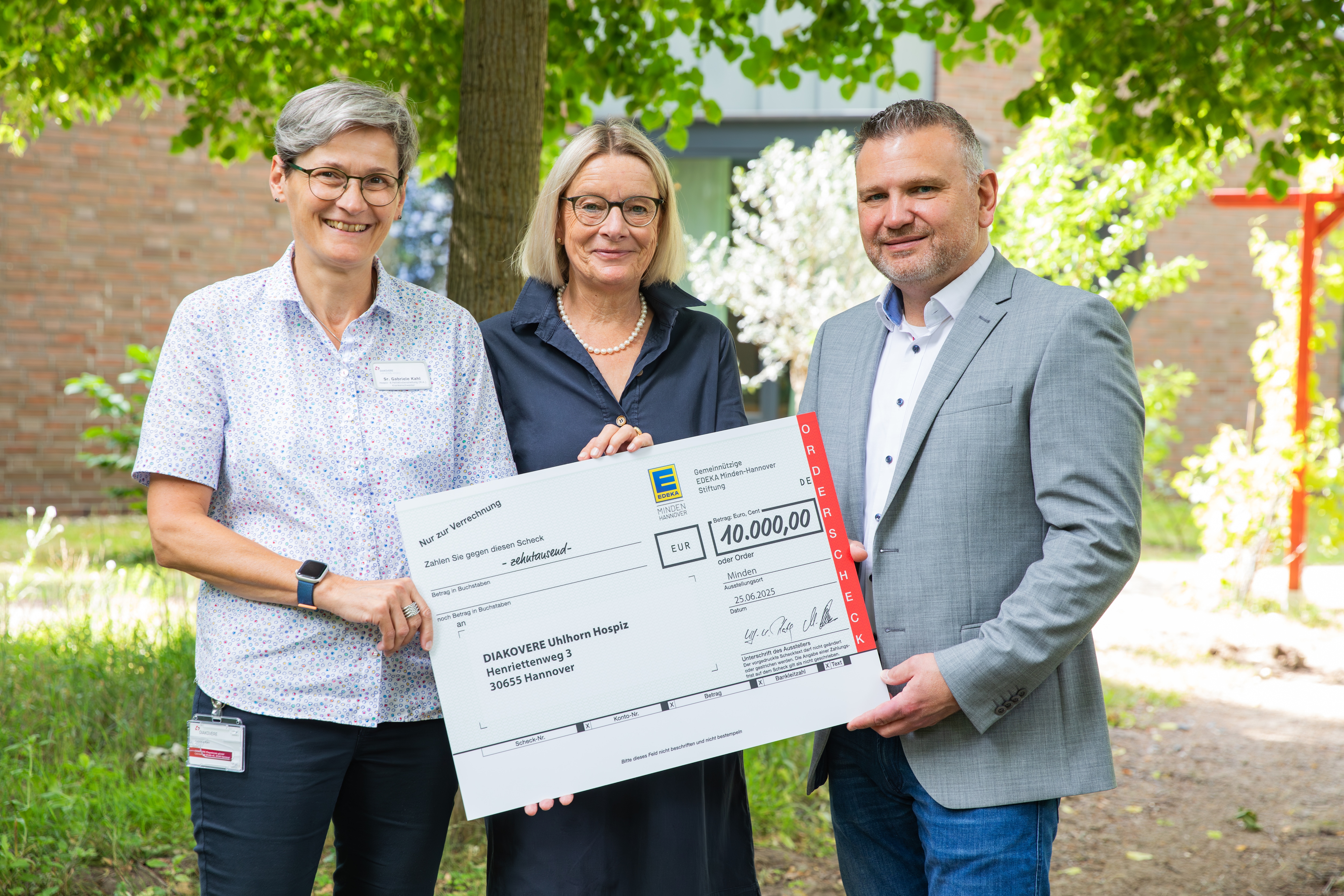 Thorsten Wucherpfennig übergibt den symbolischen Spendenscheck an Anke Reichwald und Schwester Gabriele Kahl.