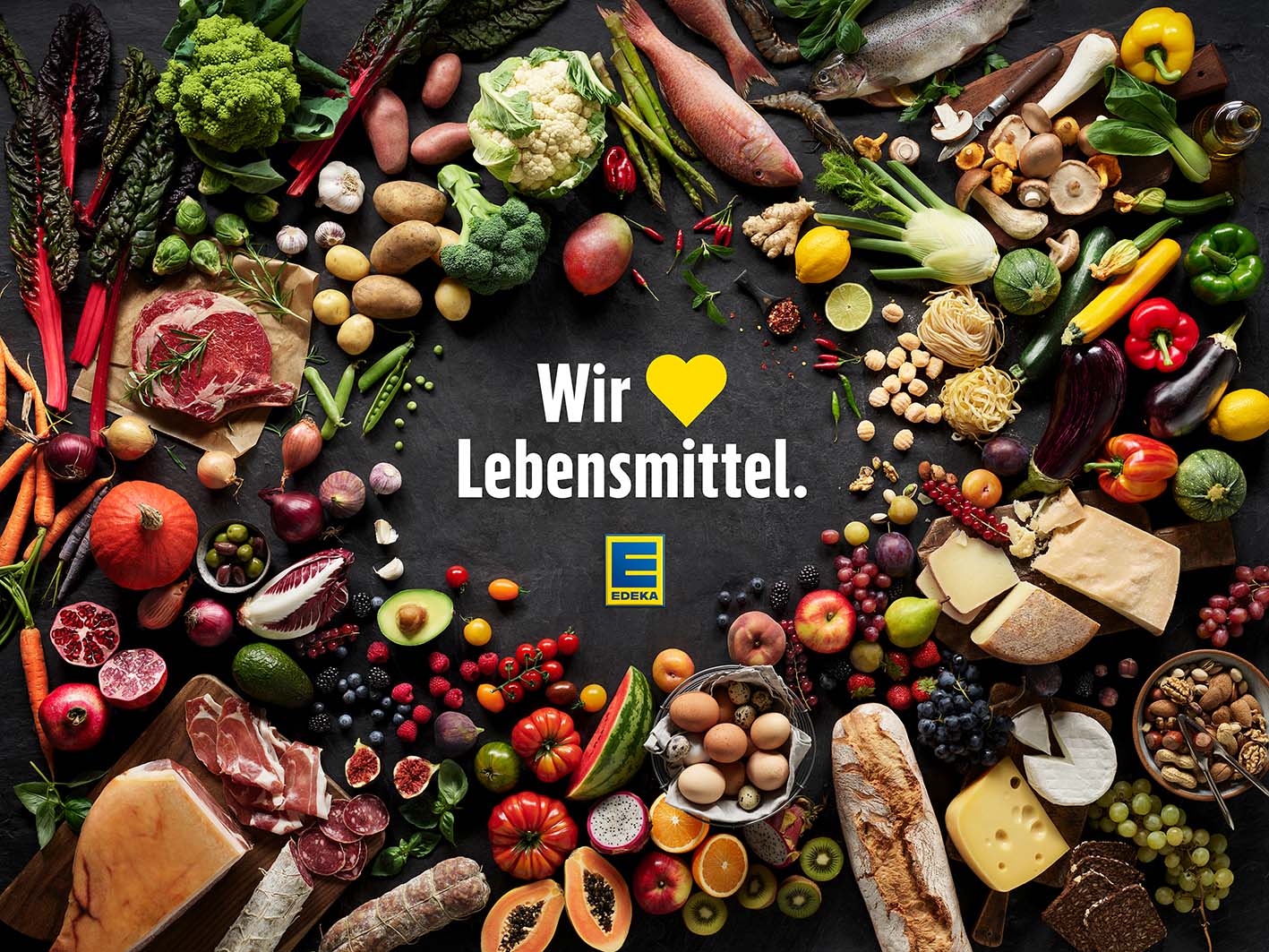 Der EDEKA-Claim "Wir lieben Lebensmittel.", umrahmt von diversen frischen Lebensmitteln.
