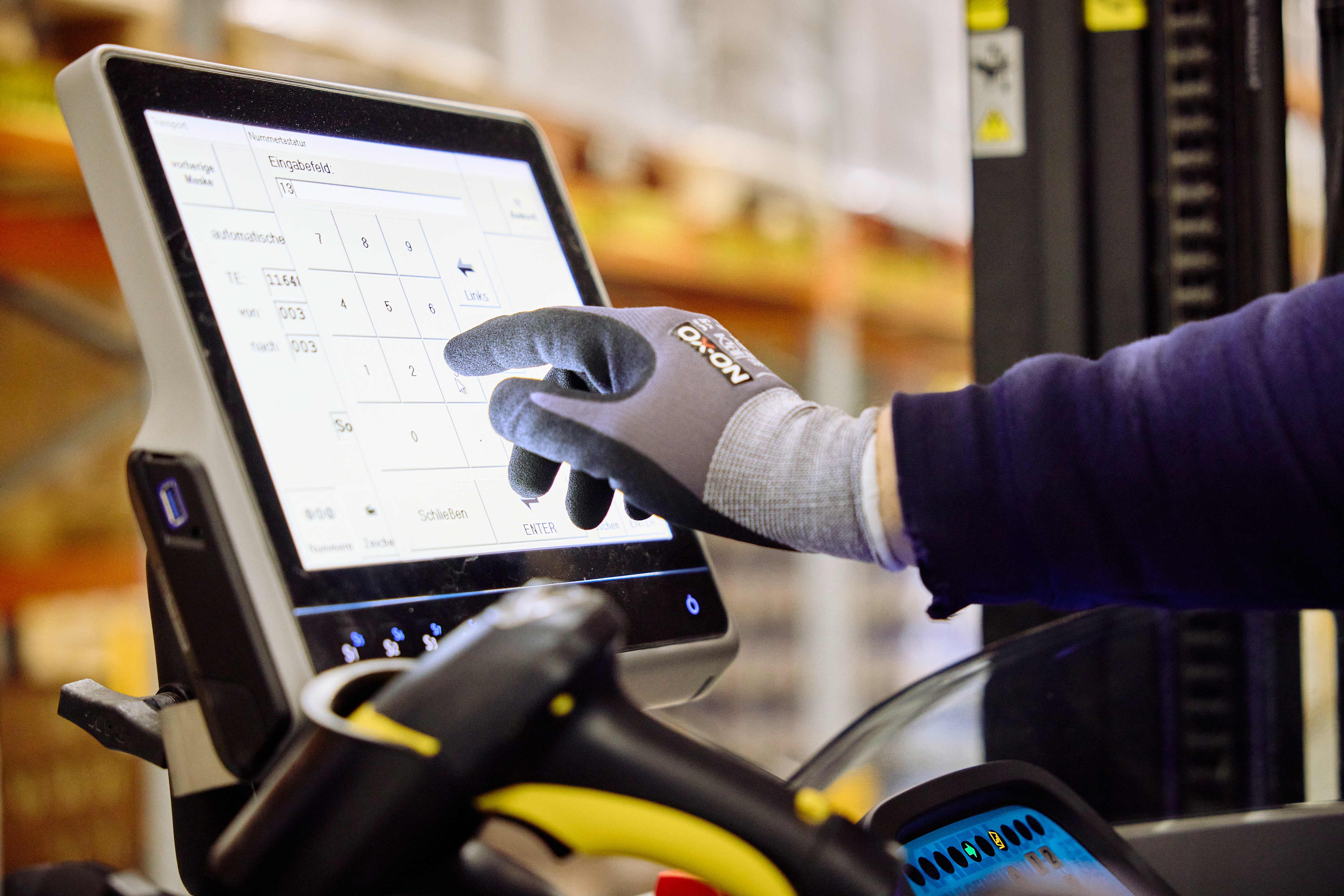 Person mit Handschuh bedient ein Touchscreen-Gerät.