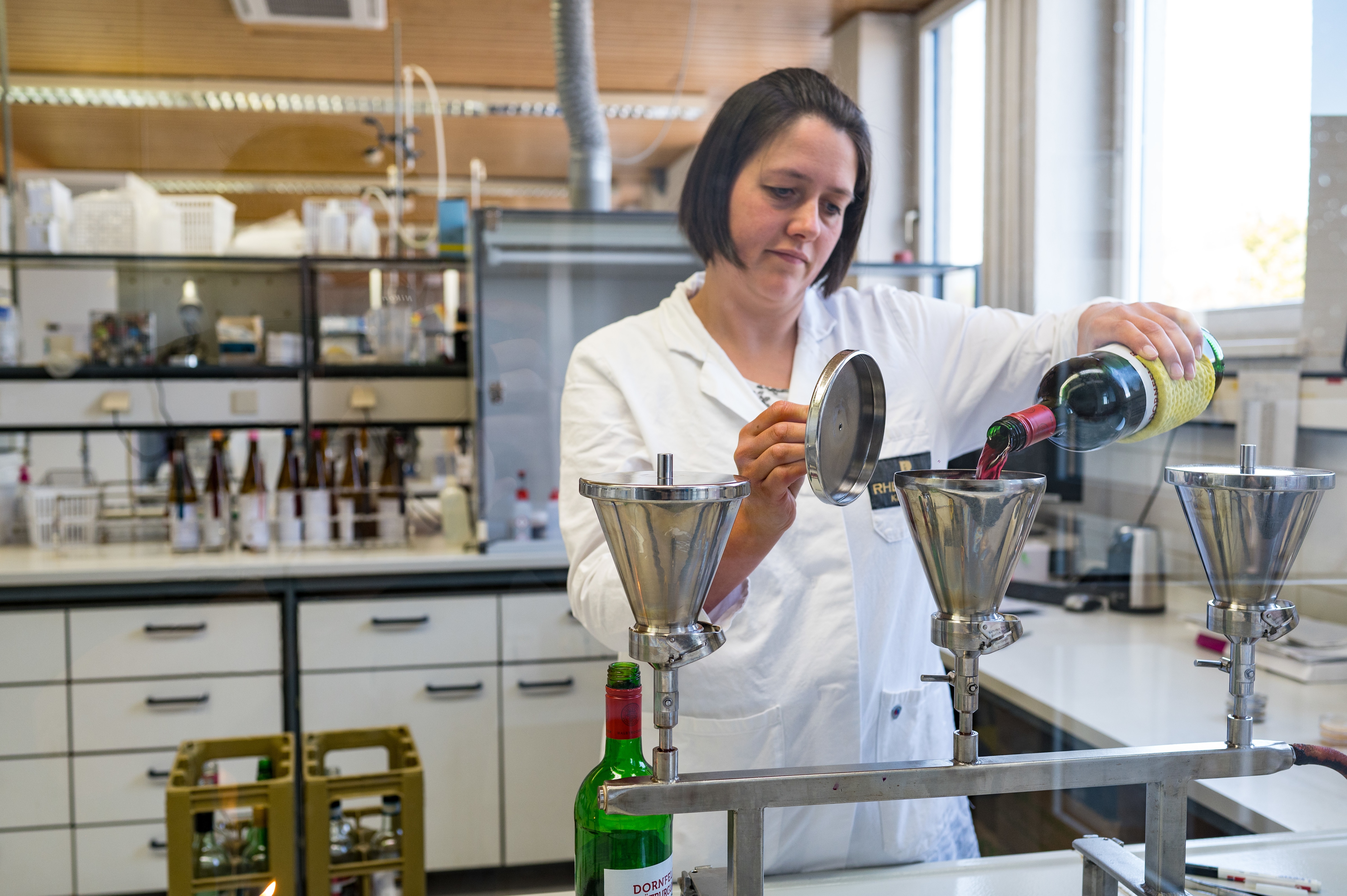 Mitarbeiterin im Labor füllt Wein in einen Filter