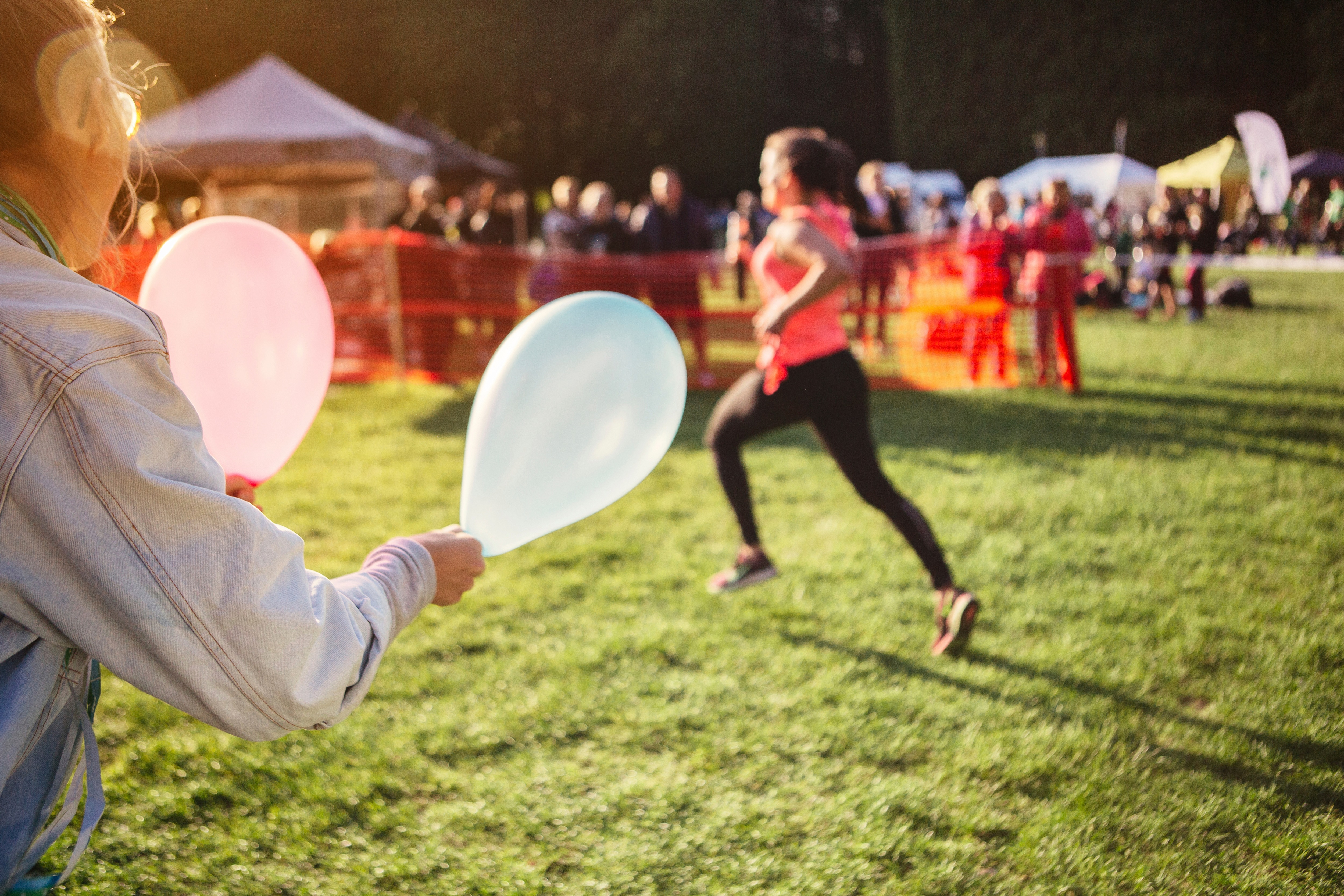 Eine laufende Frau wird mit Luftballons angefeuert. 
