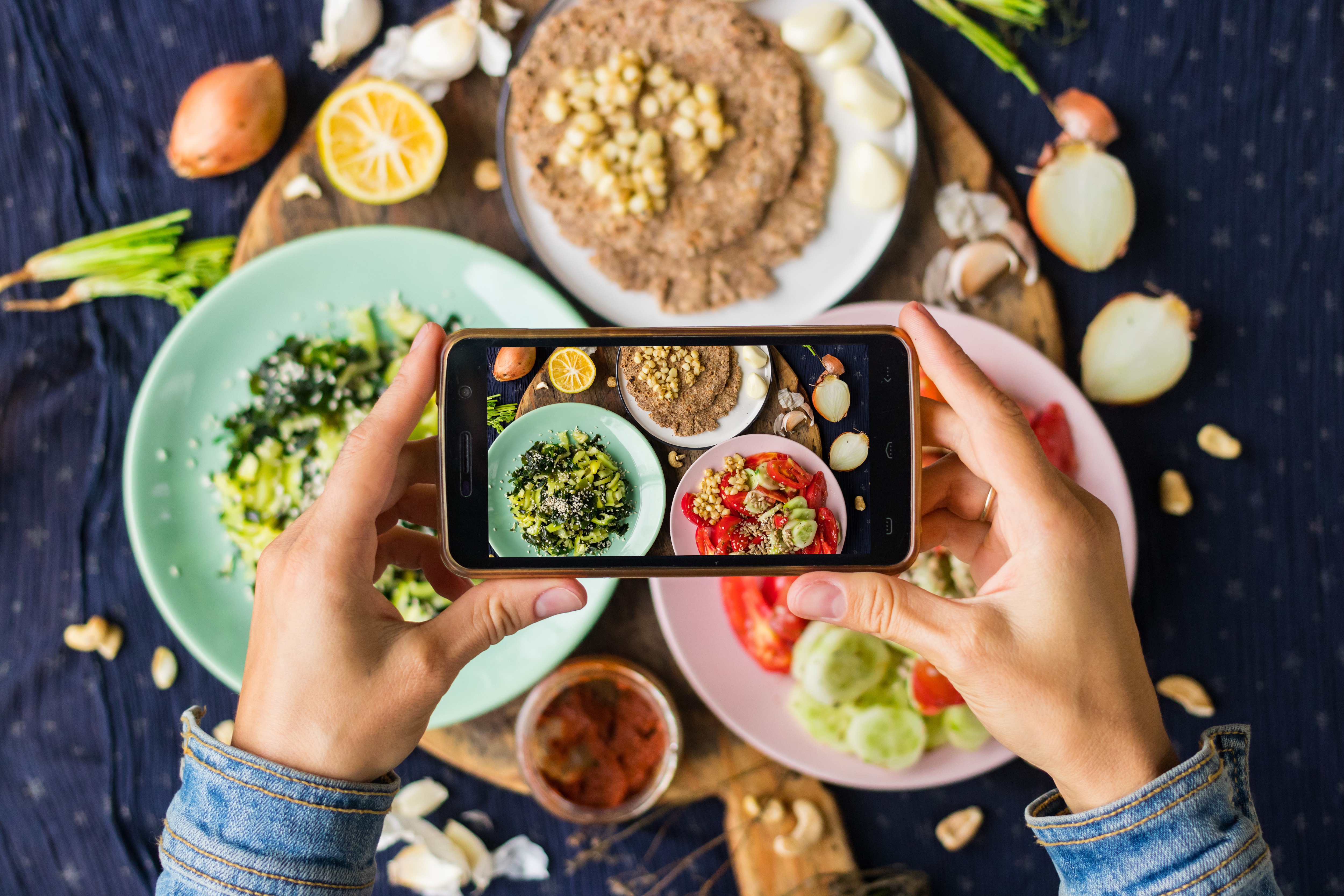 Person fotografiert Essen mit dem Smartphone.