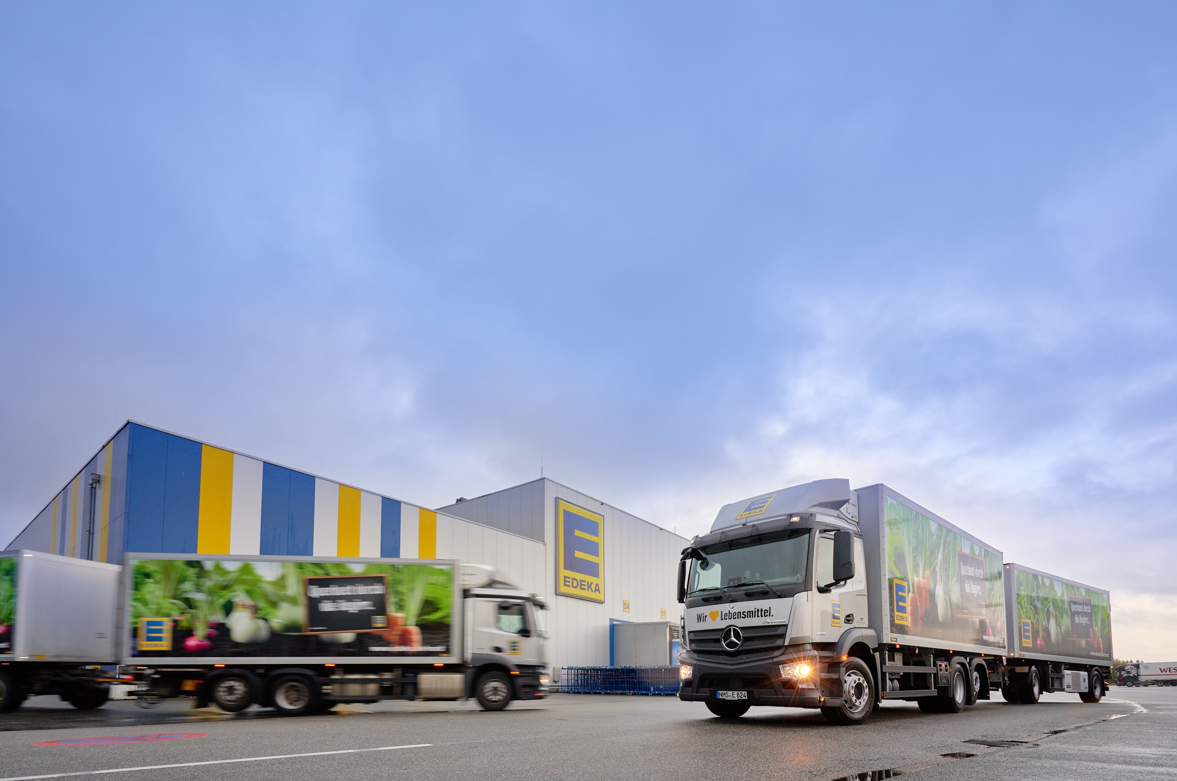Zwei Lkw fahren am EDEKA Nord-Logistikzentrum in Neumünster-Gadeland vorbei.