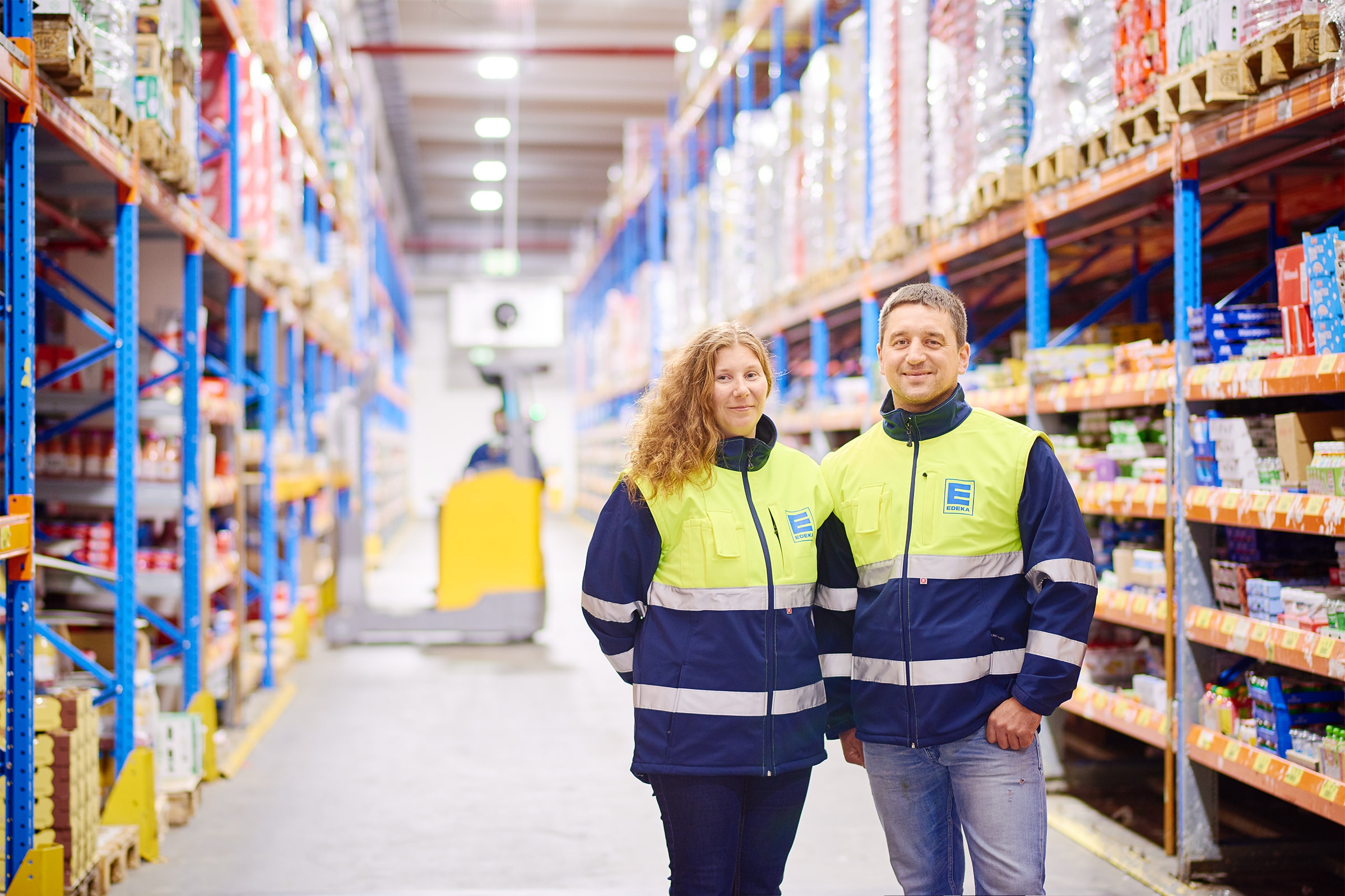 Zwei freundliche Logistik-Mitarbeitende stehen im Gang zwischen Regalen im Trockensortimentslager.