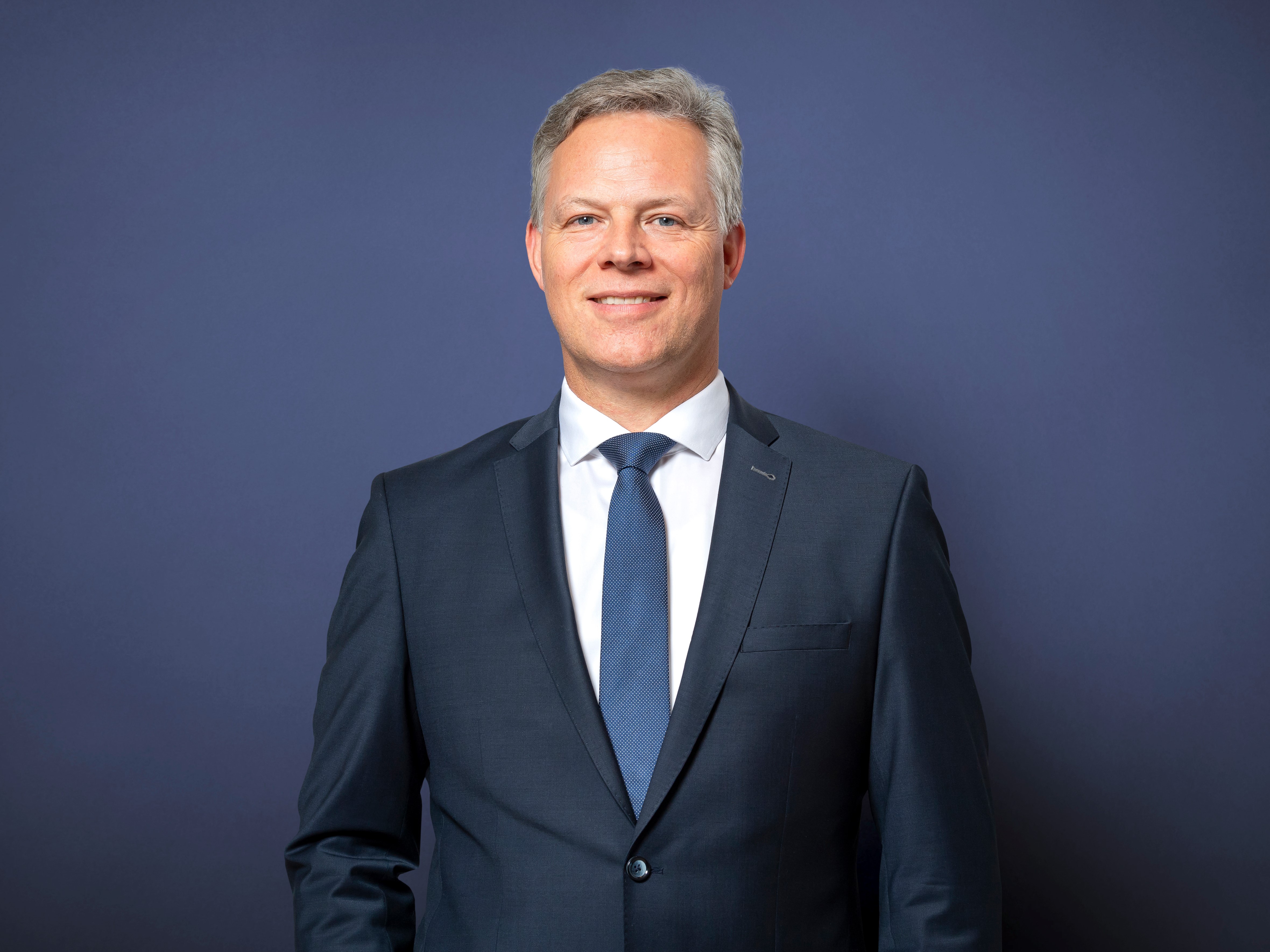 Portrait von Peter Keitel vor neutralem Hintergrund. Er trägt ein dunkelblaues Sakko.