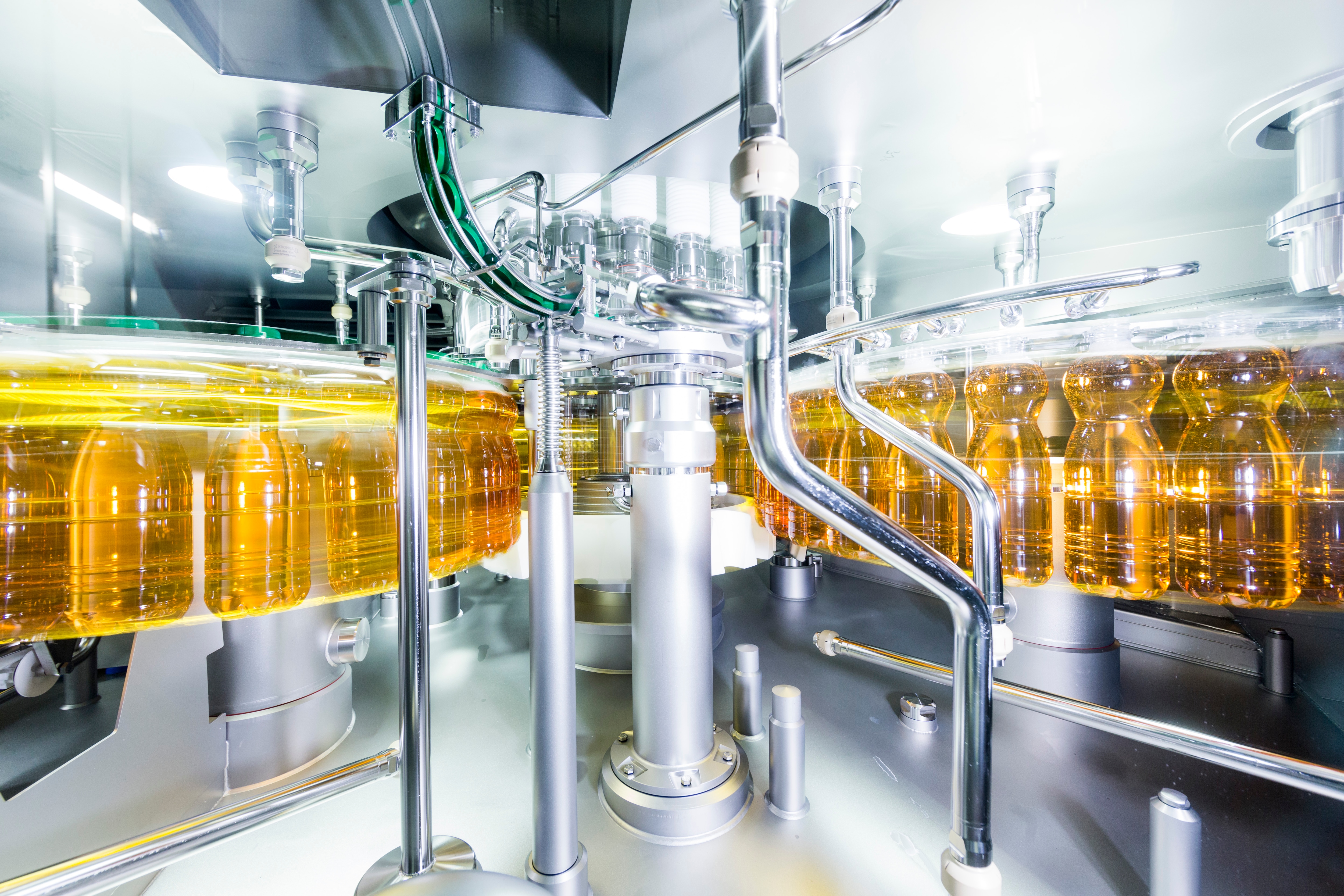 Abfüllanlage einer Saftproduktion. Goldene Flaschen mit grünen Deckeln drehen sich schnell.