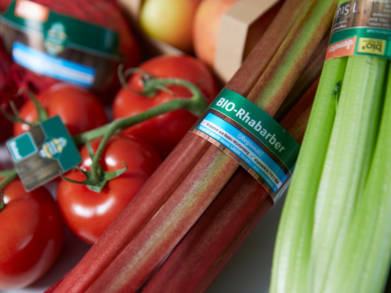 Tomaten, Bio-Rhabarber-Stangen und Stangensellerie liegen nebeneinander und sind als regional, bio oder demeter gekennzeichnet.