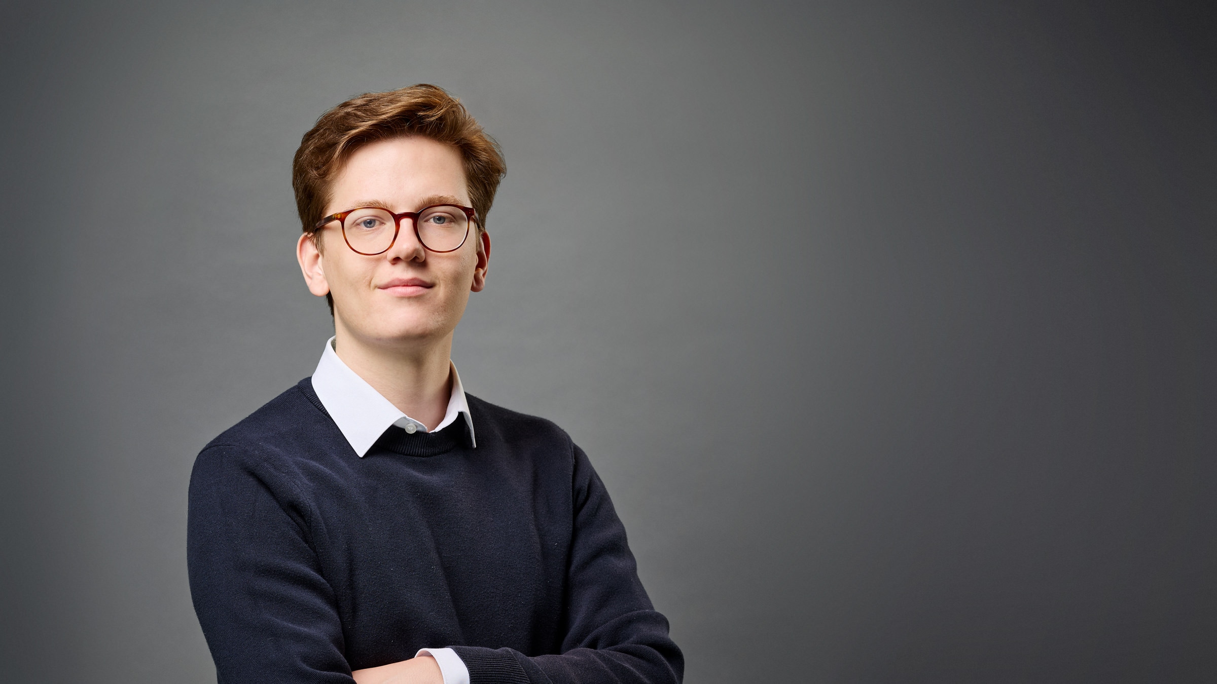 Hugo Hackmann vor grauem Hintergrund lächelt in die Kamera