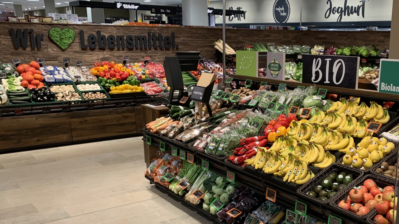 Zahlreiches Obst und Gemüse liegt in schrägen Gondeln in der Obst & Gemüseabteilung zum Kauf bereit.