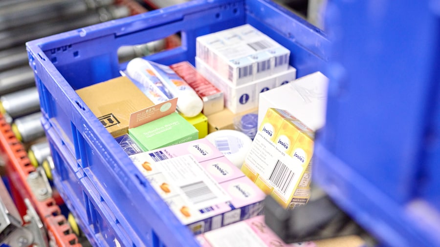 Blaue Kunststoffkiste mit verschiedenen verpackten Produkten auf einem Förderband