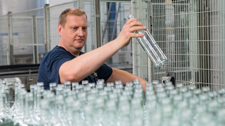 Mitarbeiter prüft leere Flaschen bei der Weinabfüllung