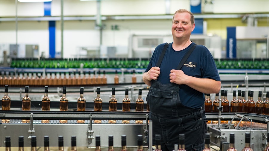 Mitarbeiter steht vor abgefüllten Weinflaschen