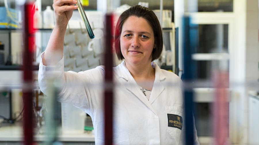 Mitarbeiterin im Labor hält ein Reagenzglas nach oben