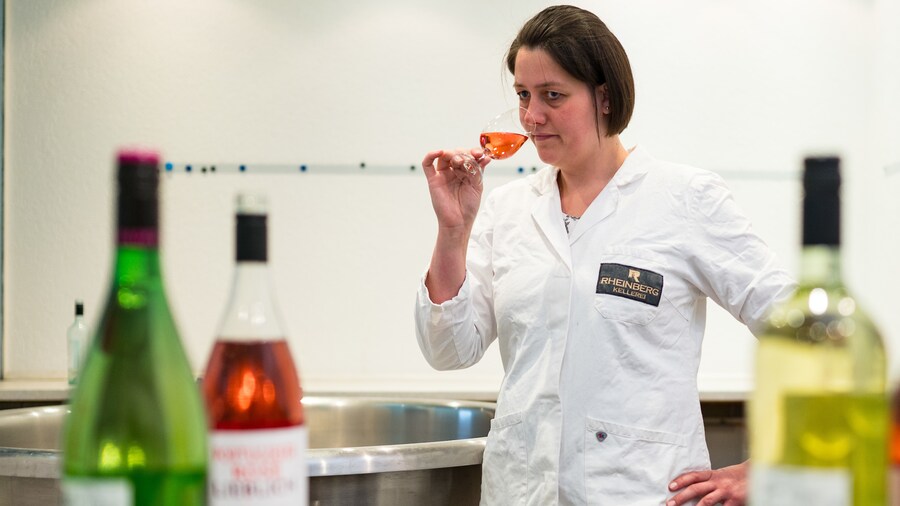 Labor-Mitarbeiterin riecht an einem Glas Wein, im Vordergrund stehen Flaschen 