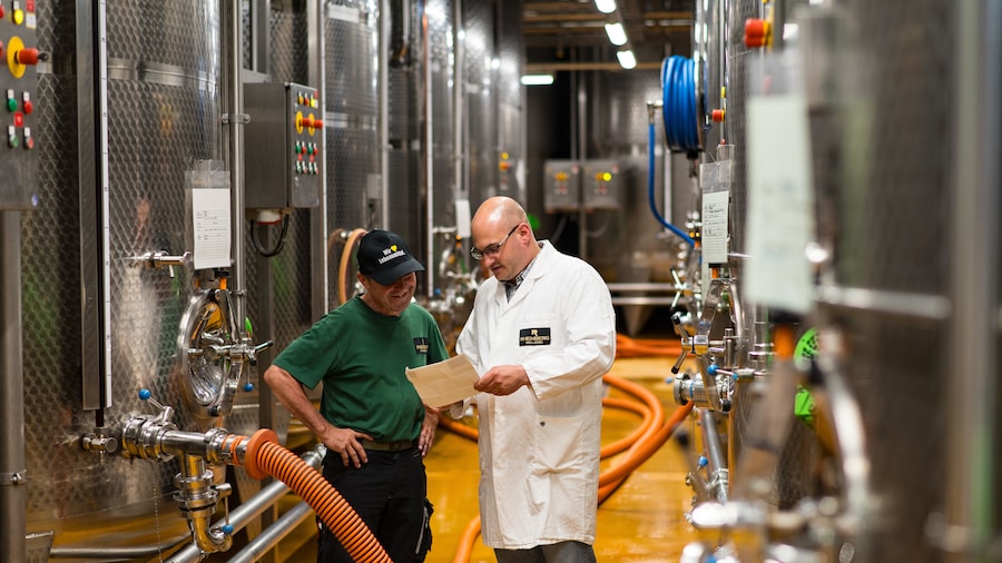 Zwei Mitarbeiter besprechen sich vor einer Abfüllanlage