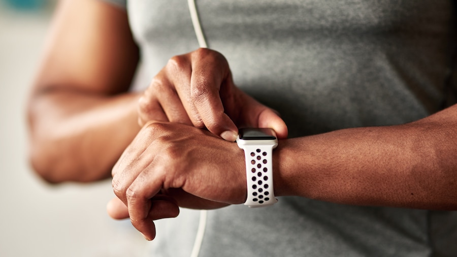 Eine Person in Sportkleidung stellt seine Armbanduhr ein. 