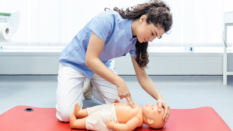 Frau führt Herzdruckmassage an einer Baby Atrappe durch. 