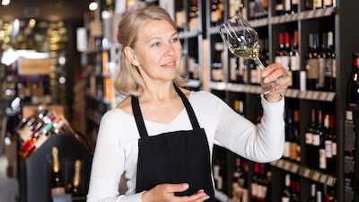 Eine Sommelière prüft mit einem Blick den Weißwein in ihrem Glas.