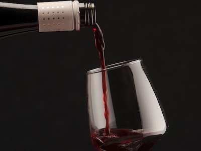 Rotwein wird aus einer Flasche in ein Weinglas geschenkt.