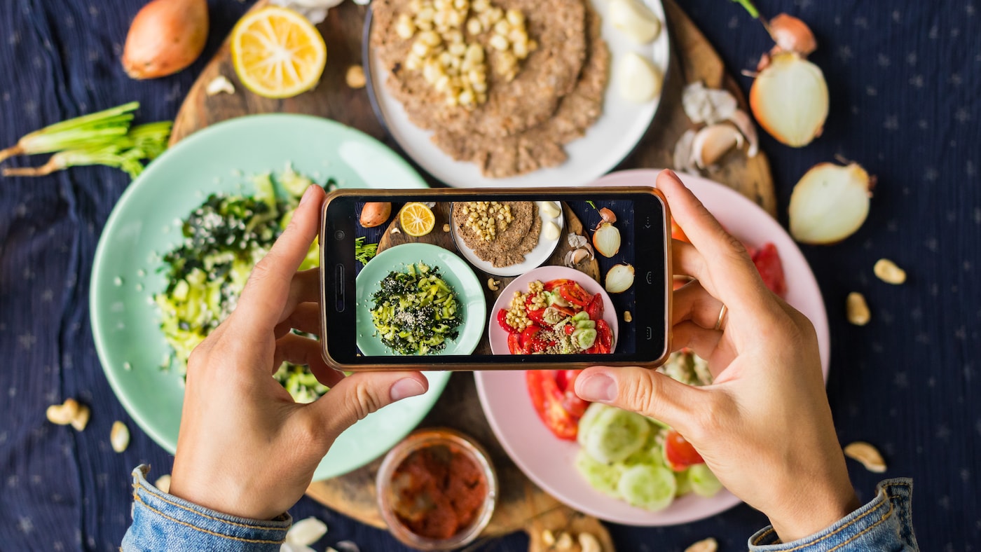 Person fotografiert Essen mit dem Smartphone.