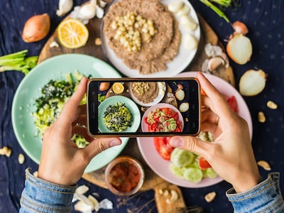 Person fotografiert Essen mit dem Smartphone.