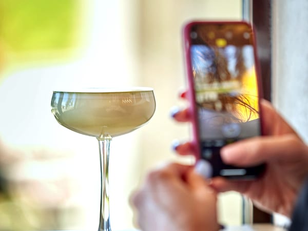 Eine Person macht mit dem Smartphone ein Foto eines Cocktails.