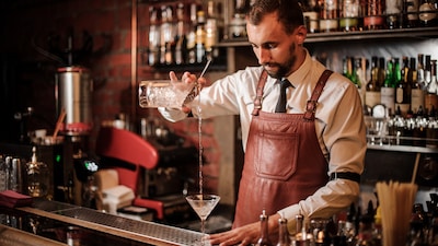 Ein Barkeeper befüllt ein Glas mit einem Mixgetränk