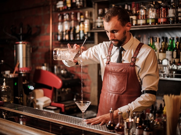 Ein Barkeeper befüllt ein Glas mit einem Mixgetränk
