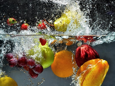 Diverse Obst-Sorten werden spritzend in Wasser geworfen.