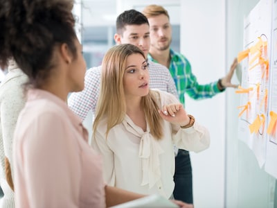 Eine Gruppe von Personen betrachtet Post-Its auf einer Wand