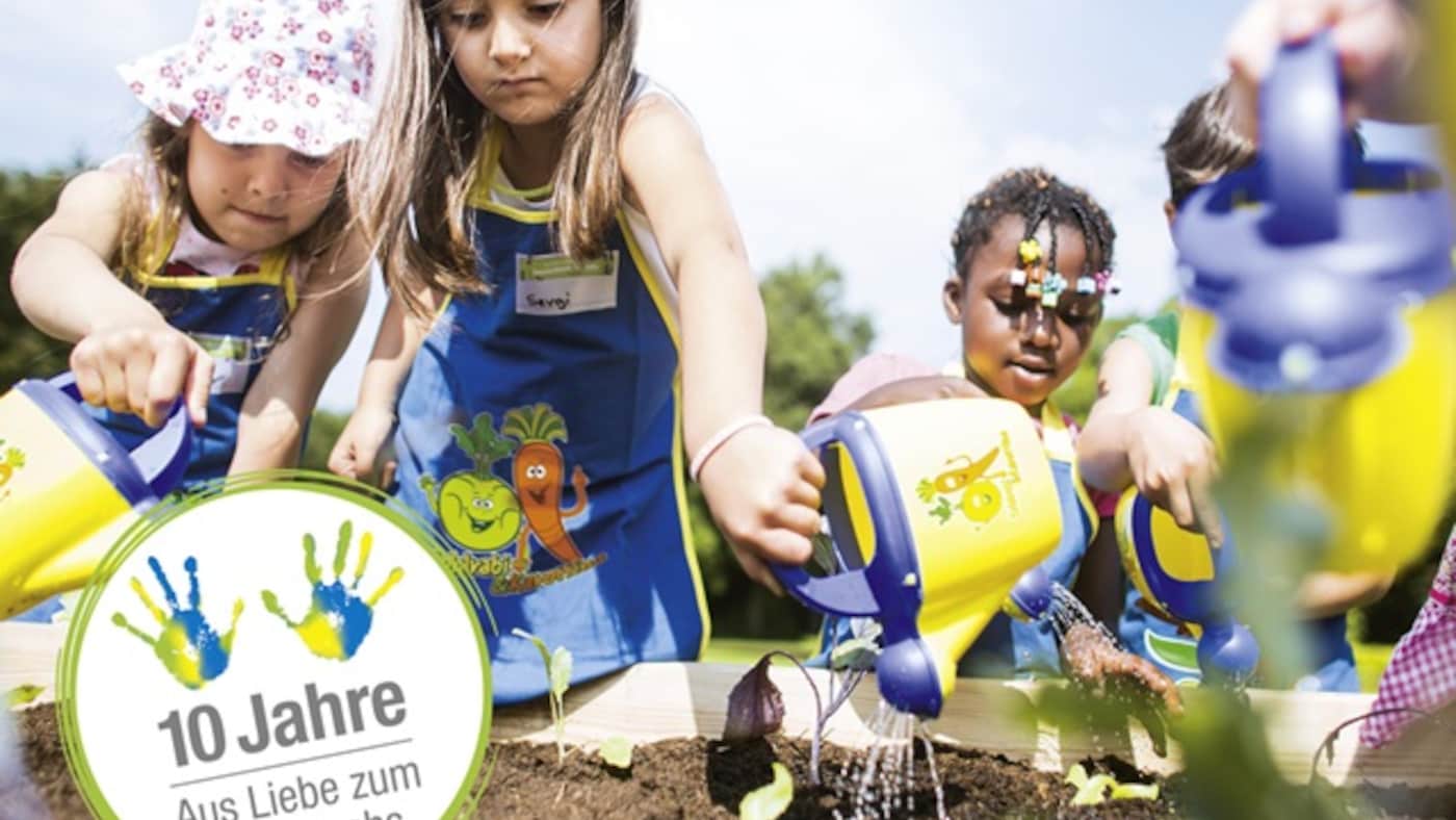 Mehrere Kinder wässern ein Gemüsebeet im Rahmen des Nachhaltigkeitsprojekts 
