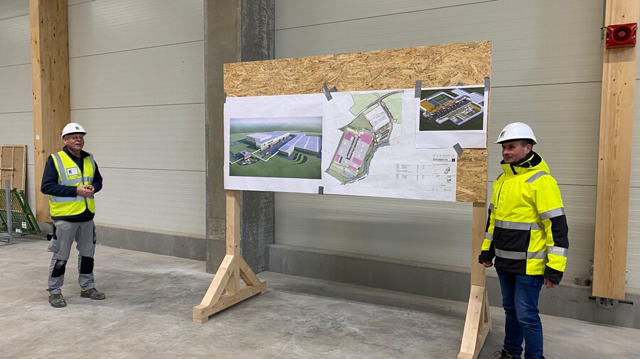 Zwei Männer präsentieren den Bauplan