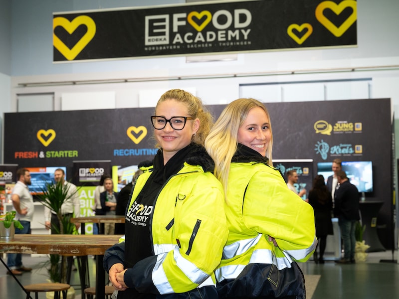 2 Mitarbeiterinnen stehen mit Rücken aneinander, auf Symposium