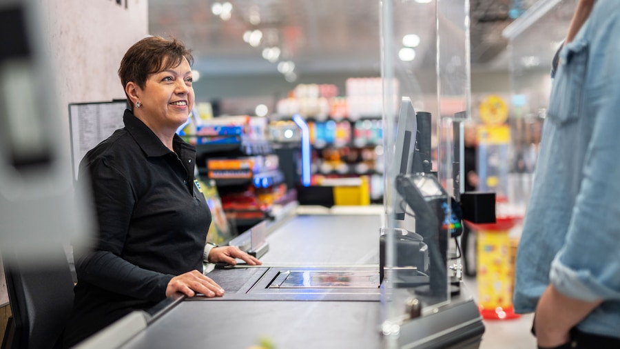 Mitarbeiterin sitzt an der Kasse