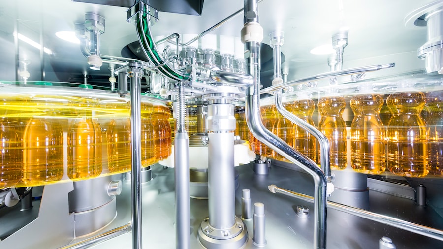 Abfüllanlage einer Saftproduktion. Goldene Flaschen mit grünen Deckeln drehen sich schnell.