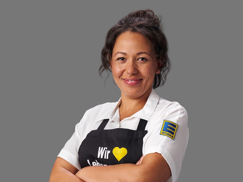 Portraitbild von Mandy Bauermeister. Sie trägt ein weißes EDEKA-Hemd und eine schwarze Schürze.
