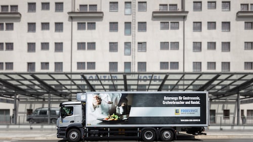 Weißer LKW von EDEKA Foodservice vor einem Hoteleingang.