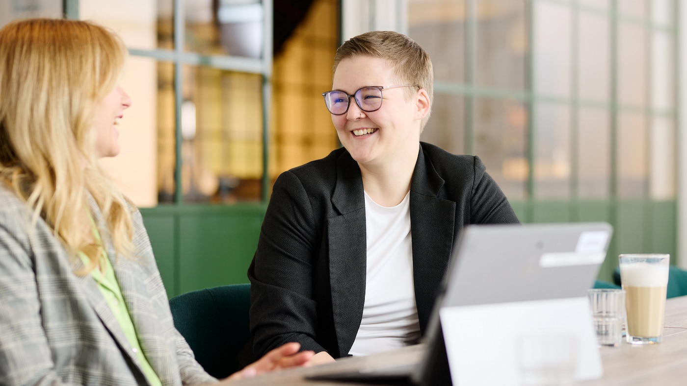 Zwei Trainees im Gespräch, beide lachen. 