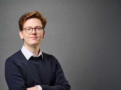 Hugo Hackmann vor grauem Hintergrund lächelt in die Kamera