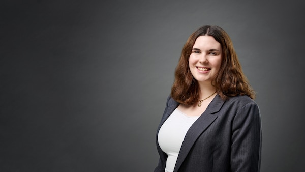 Lina Böhling lächelt vor grauem Hintergrund in die Kamera