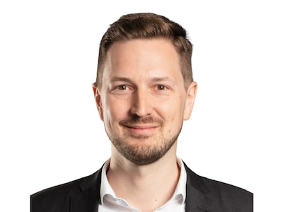 Das Bild zeigt das Portrait von Simon Zehler, er lächelt freundlich in die Kamera.
