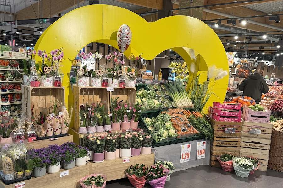 Die Blumensträuße des EDEKA Center Specht sind vor einem großen gelben Herz aufgebaut.