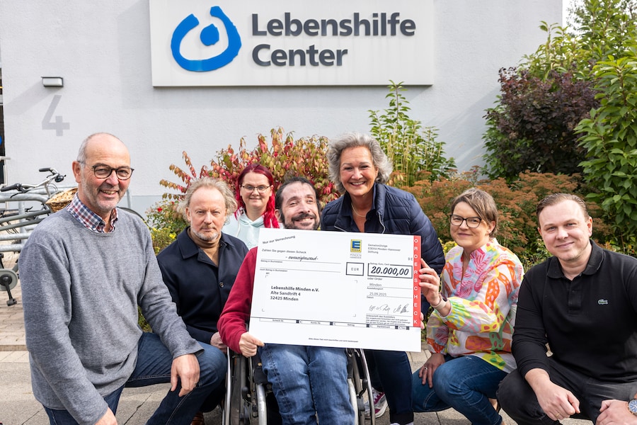 Vertreter der EDEKA Minden-Hannover Stiftung übergeben vor dem Gebäude der Lebenshilfe Minden den Spendenscheck.