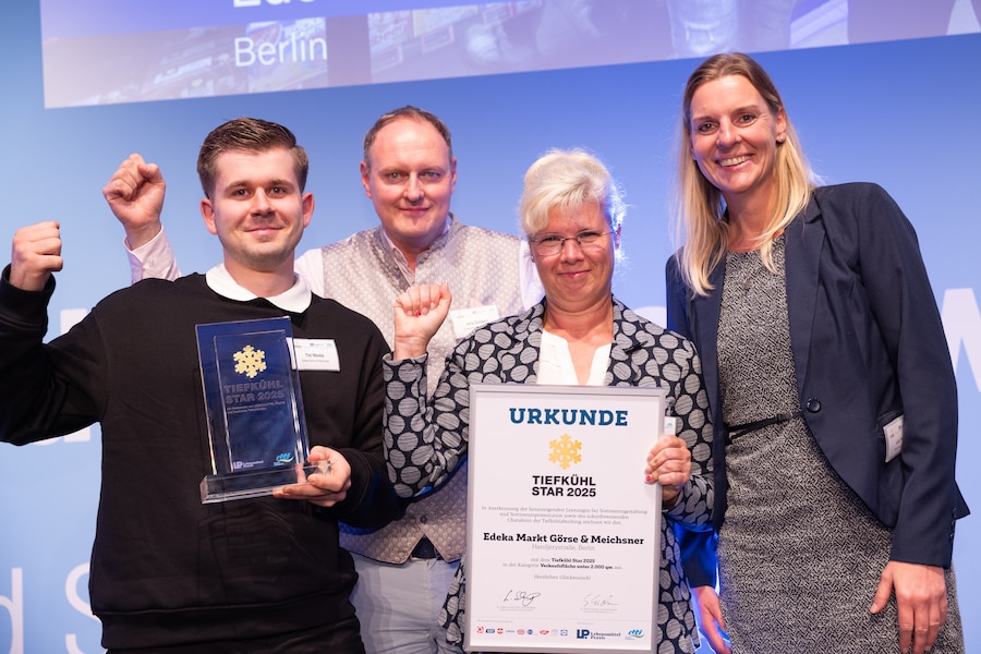 Die vier Mitarbeitenden halten die Trophäe und die Urkunde in den Händen und bejubeln ihren Sieg.