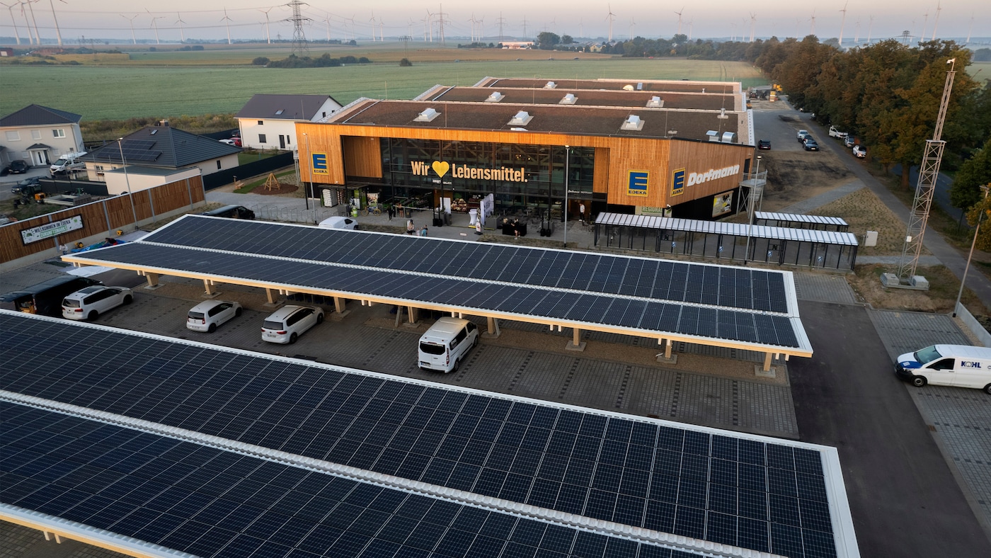 Der Zukunftsmarkt EDEKA Dorfmann in Nauen zeigt sich mit einer Holzfassade und Photovoltaik-Carports auf dem Parkplatz.