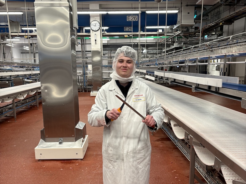 Azubi-Botschafter Hannes steht in Arbeitskleidung in der Produktionshalle des Fleischwerks.